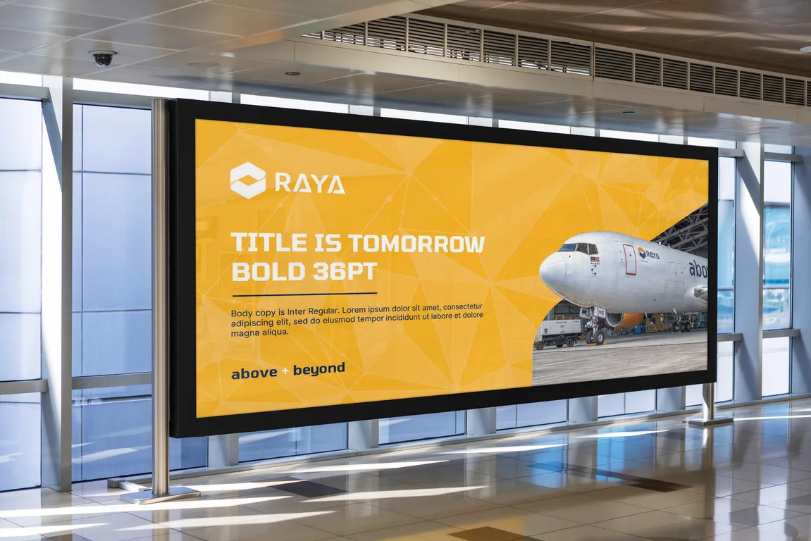 Raya Airways illuminated signage in yellow with a freighter photograph inside a terminal corridor