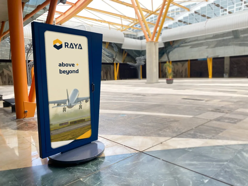 Raya Airways above and beyond standee in navy and yellow inside an airport terminal