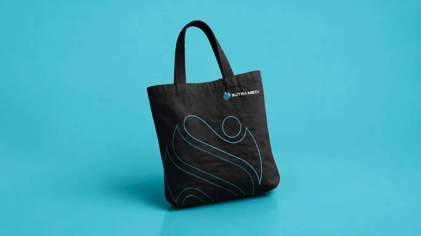 Sutra Medi-Environ black tote bag carrying the logo and turquoise line-art secondary graphic