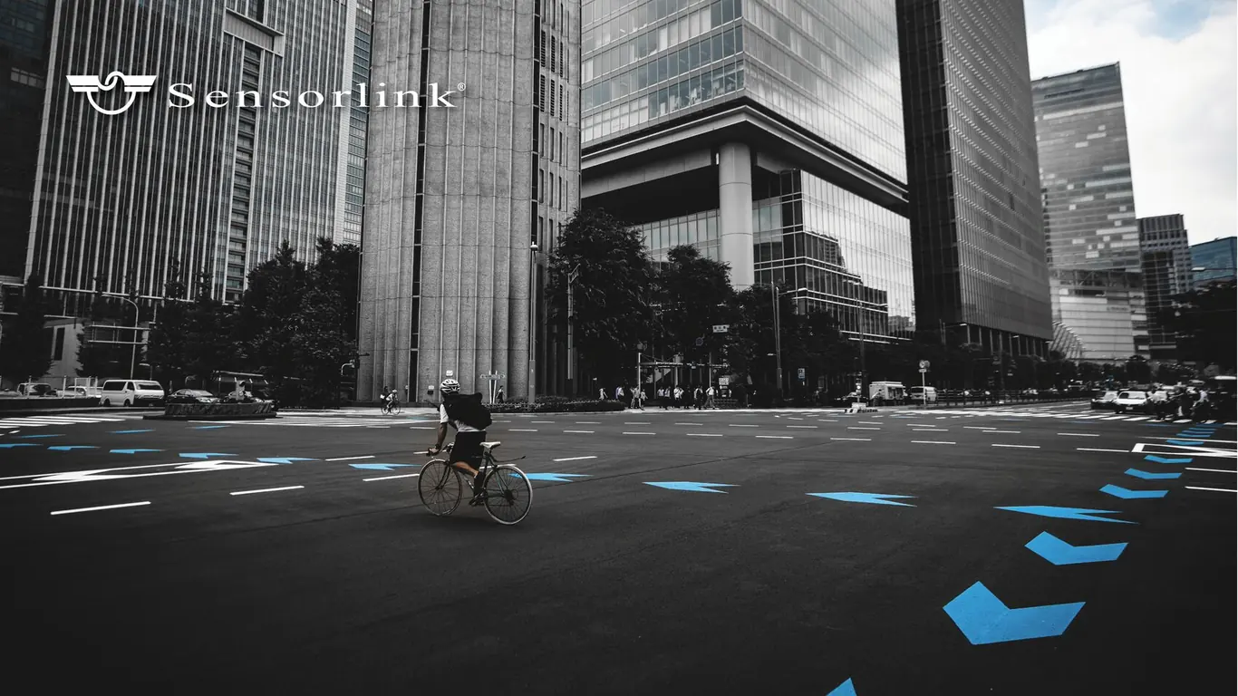 Sensorlink logo in white over a monochrome city junction with a cyclist and blue road markings